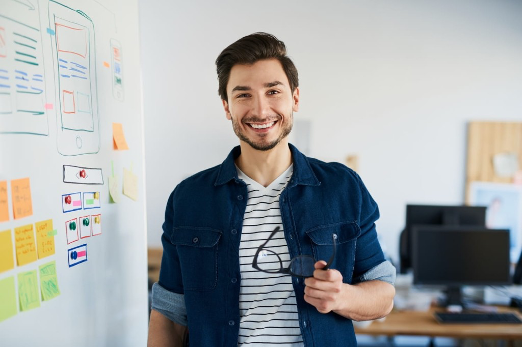 Planungsverantwortlicher steht lächelnd neben einem Whiteboard mit Planungsskizzen